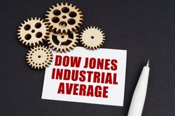 Industrial concept. On the black surface are gears, a pen and a business card with the inscription - Dow Jones Industrial Average