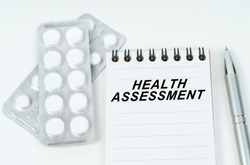 Medical concept. On a white surface are pills in a package, a pen and a notepad with the inscription - HEALTH ASSESSMENT