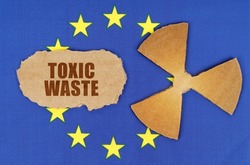 The concept of industry and radiation. On the flag of the European Union, the symbol of radioactivity and torn cardboard with the inscription - Toxic waste