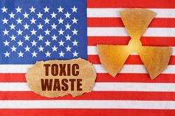 Industry and radiation concept. On the flag of the United States, there is a symbol of radioactivity and a torn cardboard with the inscription - Toxic waste
