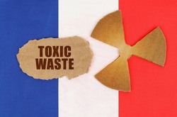 The concept of industry and radiation. On the flag of France, the symbol of radioactivity and torn cardboard with the inscription - Toxic waste