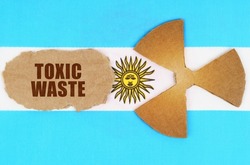 The concept of industry and radiation. On the flag of Argentina, the symbol of radioactivity and torn cardboard with the inscription - Toxic waste