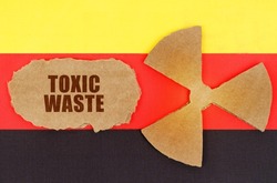 The concept of industry and radiation. On the flag of Germany, the symbol of radioactivity and torn cardboard with the inscription - Toxic waste