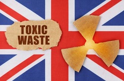 Industry and radiation concept. On the flag of Great Britain, there is a symbol of radioactivity and a torn cardboard with the inscription - Toxic waste