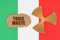 The concept of industry and radiation. On the flag of Italy, the symbol of radioactivity and torn cardboard with the inscription - Toxic waste