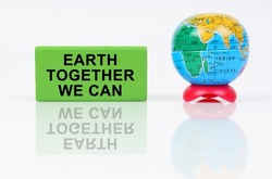Ecological concept. On a reflective surface is a globe and a green sign with the inscription - Earth Together We Can