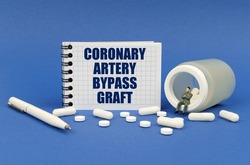 Medical concept. On a blue surface there is a jar of pills, a figure of a man, a notepad with the inscription - Coronary artery bypass graft