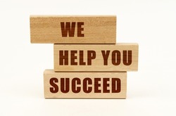 Business concept. On a white surface are wooden blocks with the inscription - We Help You Succeed
