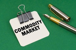 Business and industry concept. On a green surface, a pen and a sheet of paper with the inscription - Commodity market