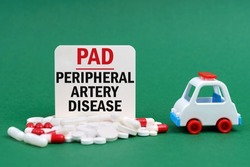 Medical concept. On a green surface, an ambulance, pills and a white sign with the inscription - Peripheral Artery Disease