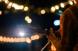 Man play acoustic guitar at outdoor concert with a microphone stand in the front, musical concept.