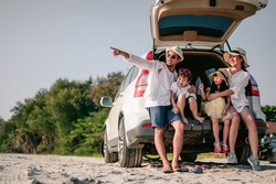 Happy asian family enjoying road trip with their favorite car. Parents and children are traveling the way to the sea or ocean.Holiday and travel family concept, Summer vacations.