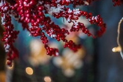 Branches with red berries covered with snow over blurred bokeh lights background , copy space, selective focus. Christmas background.
