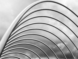 Structure with curved aluminum bars over a cloud-covered sky. Modern aluminum architecture. Modern Art. Urban art