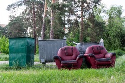 Two red leather chairs. Furniture in the trash can. Workplace in the forest. Landfill furniture. Furniture in the woods. Rest in the forest.