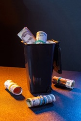 Money is like trash. Money is scattered around the trash can. Littered with money. Convolutions of money in a bucket.