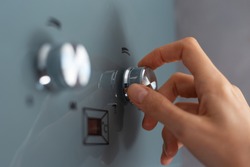 Close-up of female hand adjusting temperature of water heater. Modern home gas fired boiler.