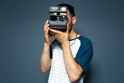 Studio portrait of young man photographer making photo with polaroid camera.