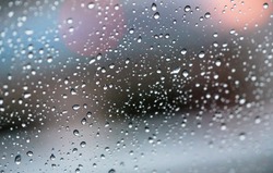 Rain drops on a window with abstract lights with selective focus area. Bokeh background concept.