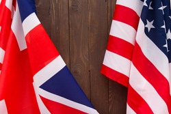 UK flag and USA Flag on wooden brown background.