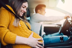 Pregnant woman starting to feel pain and contractions while her worried husband driving a car. She is ready to give birth in a car.