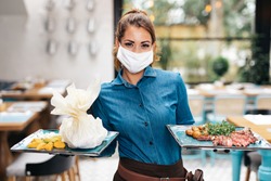 Beautiful young waitress with face protective mask working in exclusive restaurant. Coronavirus or Covid-19 concept.