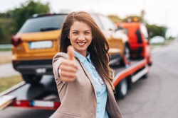 Elegant middle age business woman is happy and satisfied with fast and reliable towing service for help on the road. She showing thumb up. Roadside assistance concept.