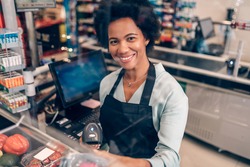 Portrait of beautiful smiling African American cashier working at a grocery store.
