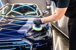 Car detailing - Man with orbital polisher in repair shop polishing car. Selective focus.	