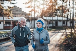An older married couple enjoys exercising and jogging on a beautiful sunny winter day.