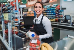 Beautiful young female cashier working at a grocery store.