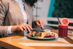 A middle-aged businesswoman enjoys a healthy meal and fresh beetroot and grapefruit juice at the organic food restaurant.