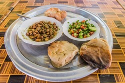 Traditional meal in Sudan - fuul (stew of cooked fava beans), salad and bread.