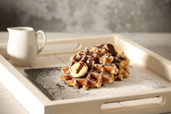 On the table Belgian banana waffles in powdered sugar	