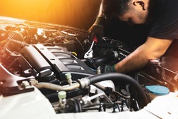 The auto mechanic hand wearing black gloves is fasten the bolt with the socket wrench to repairing of the car engine