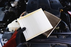New air filter in a hand and old filthy filter placed on the car engine compartment, Automobile maintenance service business concept