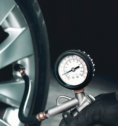Mechanic testing the tire pressure of a car with tire pressure gauge in the auto repair garage