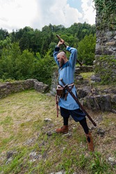 warrior with thick beard brandishes an ax, an image of historical re-enactment among the medieval ruins