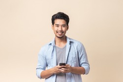 Portrait young Asian man handsome in formal shirt using smartphone trading or chatting on brown isolated studio background.