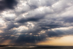 Spectacular and dramatic cloud formations with sun rays shining through gaps in the clouds just after sunrise over the sea at Jeffreys Bay