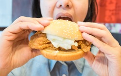 Woman eat a hamburger, junk food.Unhealthy concept.