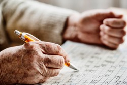 hand of a senior woman , sudoku, crossword