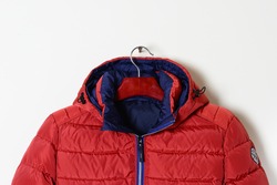 Part of a bright red jacket is a down jacket with a hood and an unbuttoned collar. Winter outerwear for men. Close-up.