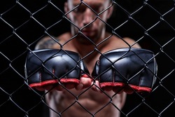 Dramatic image of a mixed martial arts fighter standing in an octagon cage. The concept of sports, boxing, martial arts. 