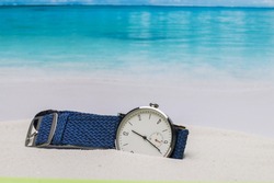 man wrist watch on the sand beach near water