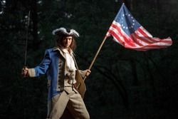 Soldier patriot rebel during war of independence of  United States with flag preparing to attack with sword