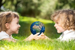 Children`s holding world in hands against green spring background. Earth day concept. Elements of this image furnished by NASA