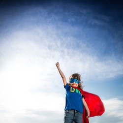 Superhero kid against dramatic blue sky background