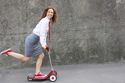 Happy businesswoman riding scooter. Outdoor portrait of young woman. Back to work, start up and business idea concept