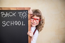 School kid in class. Happy child holding blackboard blank. Education concept